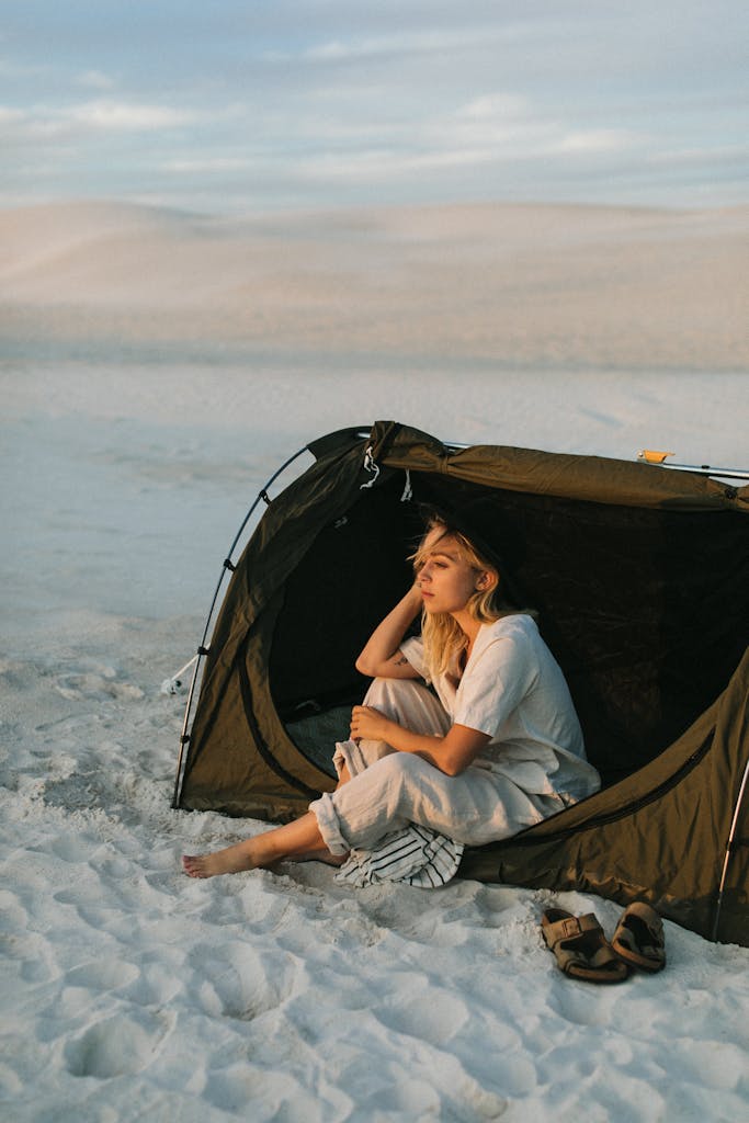 Dreamy tourist in tent contemplating desert during summer trip